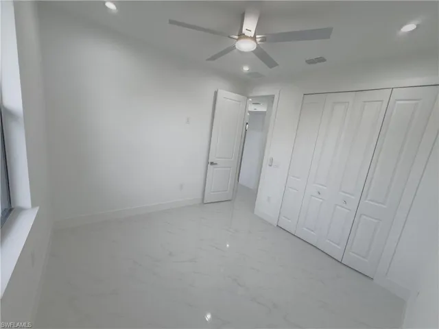 Unfurnished bedroom featuring light marble finish flooring, recessed lighting, ceiling fan, and a closet