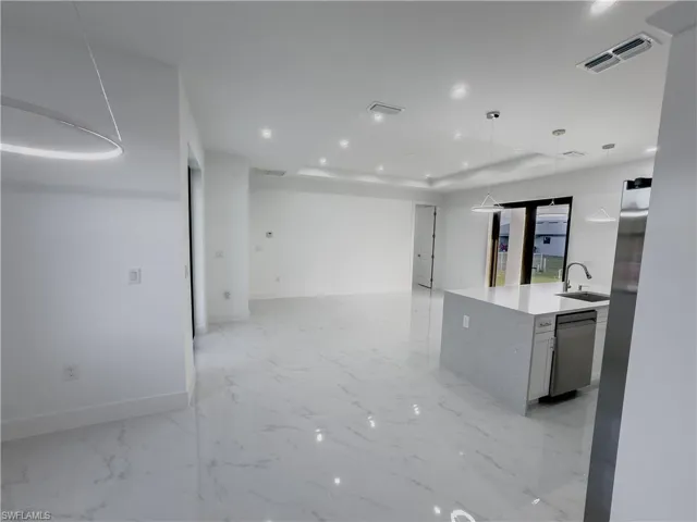 Kitchen featuring light stone counters, open floor plan, pendant lighting, recessed lighting, and dishwasher