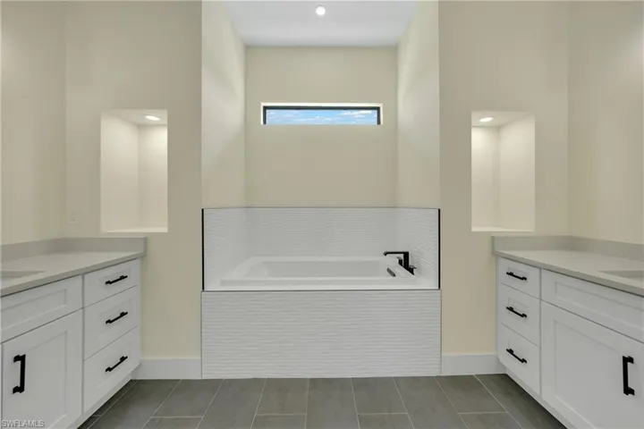 Bathroom featuring two vanities, a bath, and recessed lighting