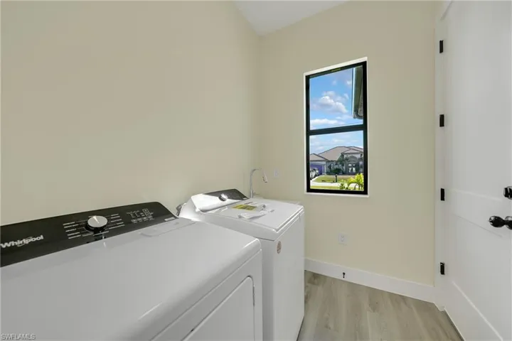 Laundry room with light wood finished floors and washer and clothes dryer