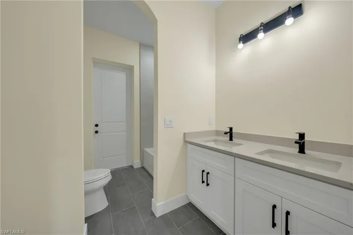 Full bathroom featuring double vanity, a bathtub, and dark tile patterned floors