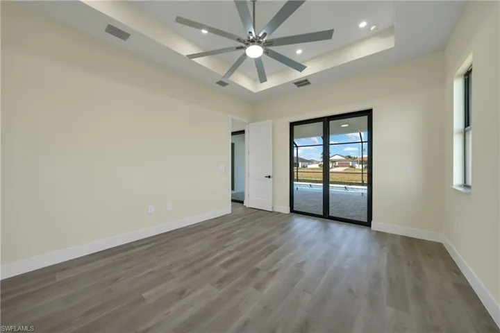 Unfurnished room featuring a tray ceiling, recessed lighting, light wood-style flooring, and ceiling fan