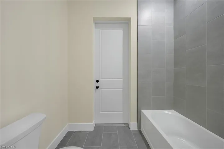 Bathroom with a tub and dark tile patterned floors