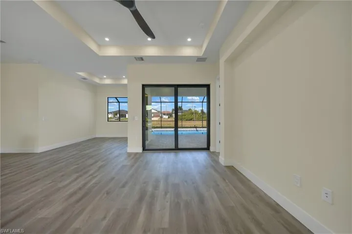 Unfurnished living room featuring a tray ceiling, light wood-style flooring, a ceiling fan, and recessed lighting