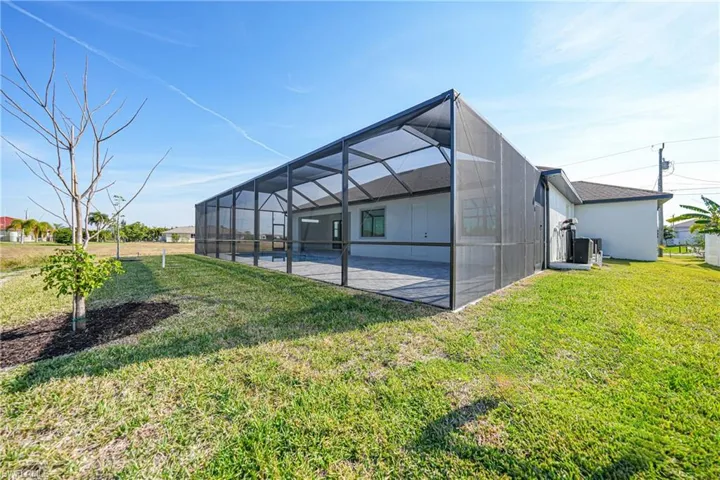 Rear view of house with a sunroom, glass enclosure, a yard, and a pool