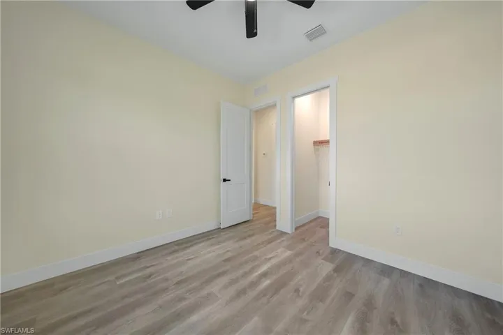 Unfurnished bedroom featuring a spacious closet, light wood-style flooring, and a ceiling fan