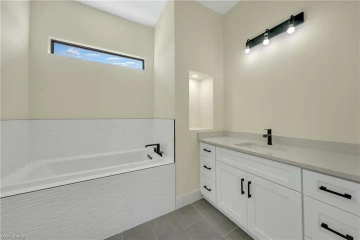 Bathroom with vanity, a garden tub, and light tile patterned floors