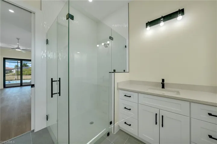 Bathroom featuring vanity, a stall shower, light tile patterned floors, and recessed lighting