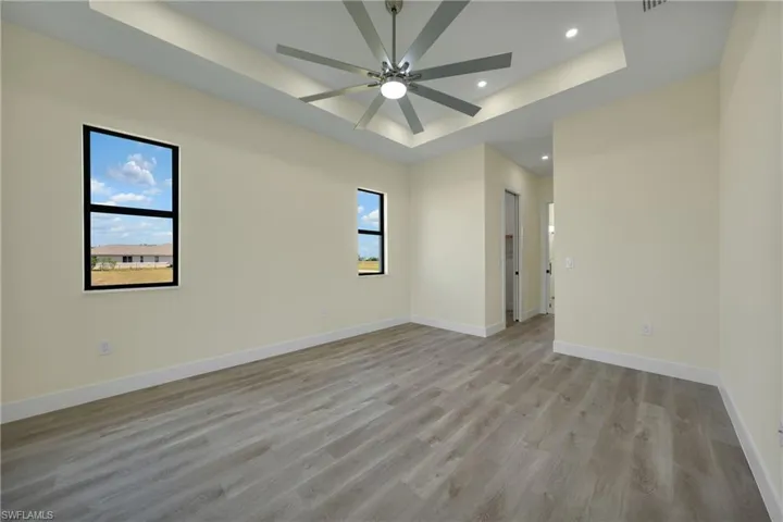 Spare room with a tray ceiling, light wood-style floors, recessed lighting, and a ceiling fan