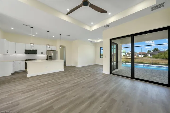 Unfurnished living room featuring a tray ceiling, light wood finished floors, a ceiling fan, and recessed lighting
