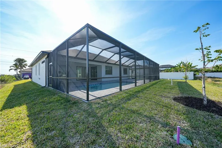 Back of house with a sunroom, an outdoor pool, glass enclosure, a yard, and a patio area