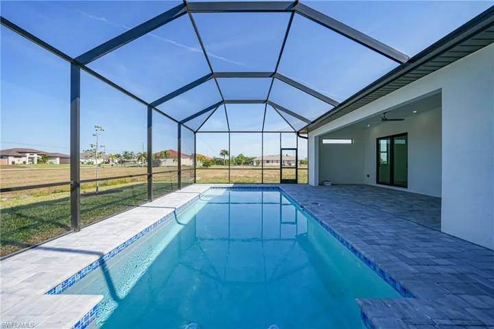 Swimming pool featuring a yard, glass enclosure, a sunroom, and a patio area