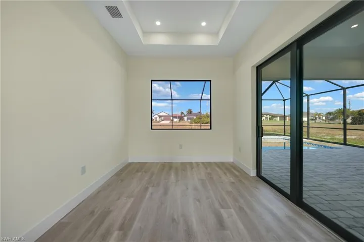 Spare room with a sunroom, light wood-style flooring, a raised ceiling, and recessed lighting