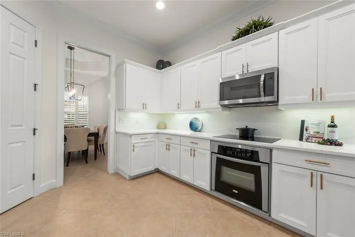 Kitchen featuring quartz countertops, white shaker cabinetry with gold hardware, stainless steel appliances, and recessed lighting