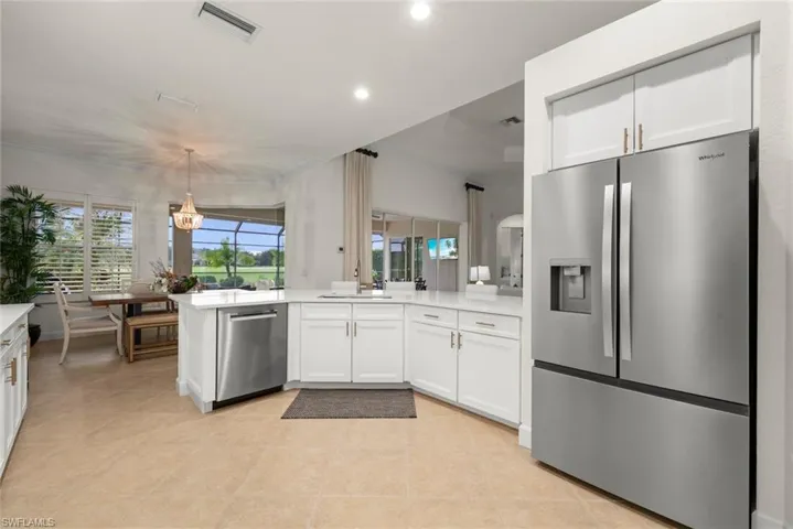 Modern kitchen featuring white cabinetry, stainless steel appliances, light-toned tile flooring, and light colored quartz countertops