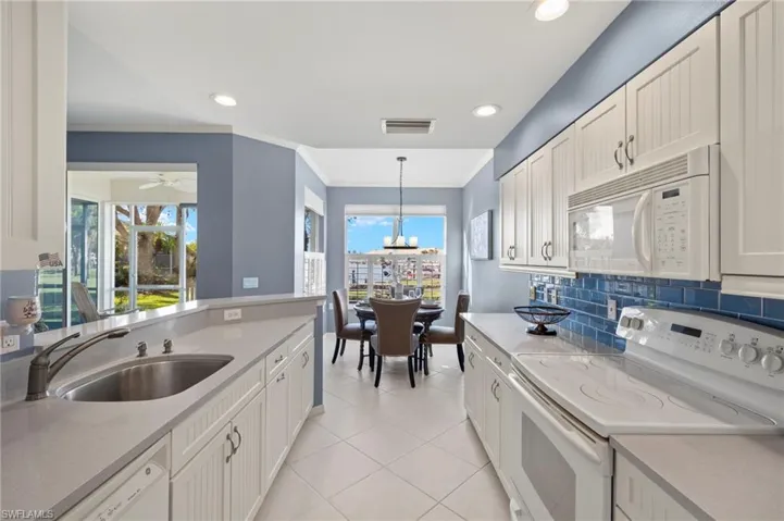 Kitchen featuring white cabinetry, white appliances, sink, and hanging light fixtures