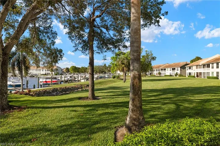 View of community with a dock, a water view, and a lawn