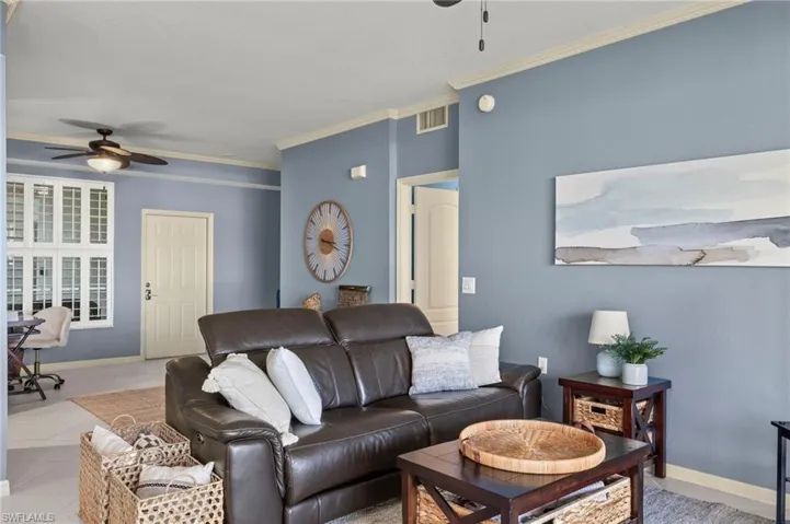 Tiled living room with ceiling fan and ornamental molding