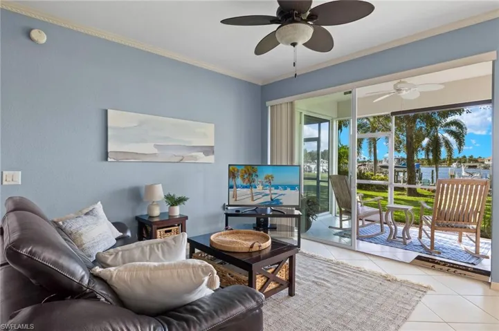 Living room with a wealth of natural light, crown molding, light tile patterned floors, and ceiling fan