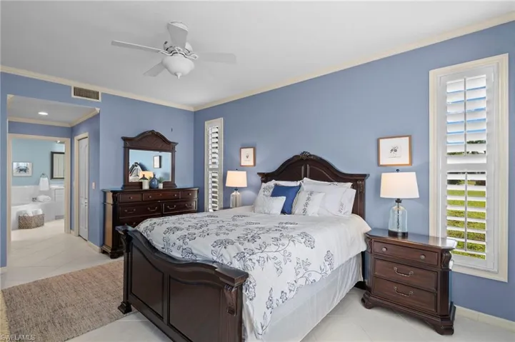 Tiled bedroom with connected bathroom, ceiling fan, a closet, and ornamental molding