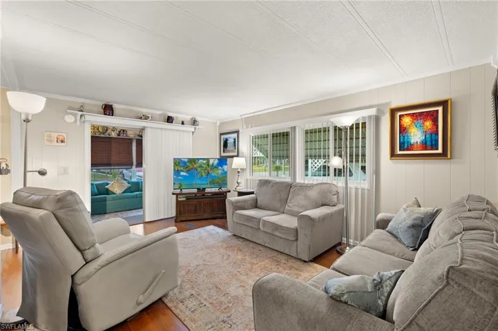 Living area featuring wood finished floors, wood walls and ornamental molding