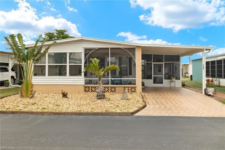Front of Home featuring a Carport, Sunroom, and Decorative Driveway