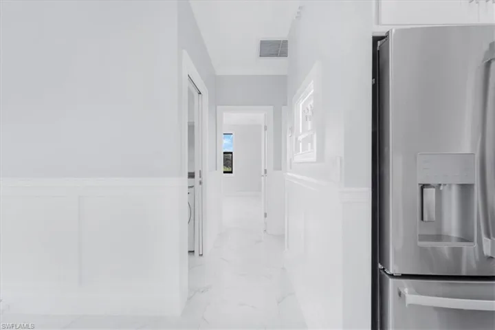 Hall with a wainscoted wall and light marble finish flooring