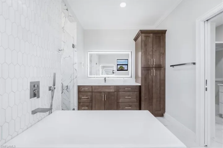 Full bath featuring vanity, a soaking tub, a marble finish shower, crown molding, and light marble finish floors