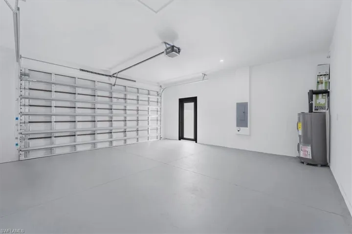 Garage featuring water heater, electric panel, and a garage door opener