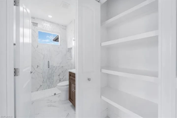 Full bathroom featuring a marble finish shower, vanity, and light marble finish flooring