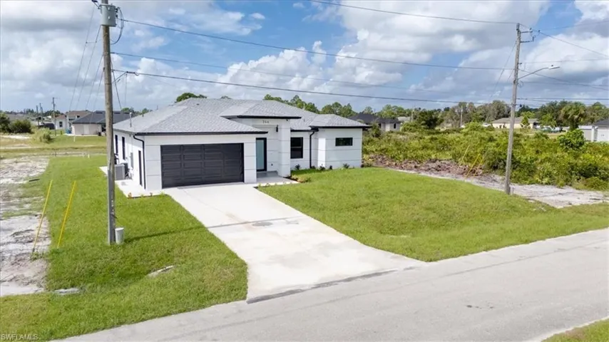 View of front of property with a front yard, stucco siding, driveway, a garage, and a shingled roof