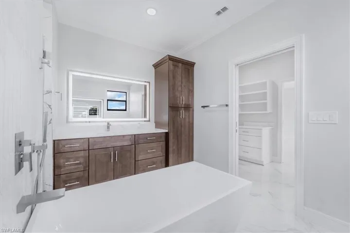 Full bathroom featuring vanity, a freestanding tub, and ornamental molding