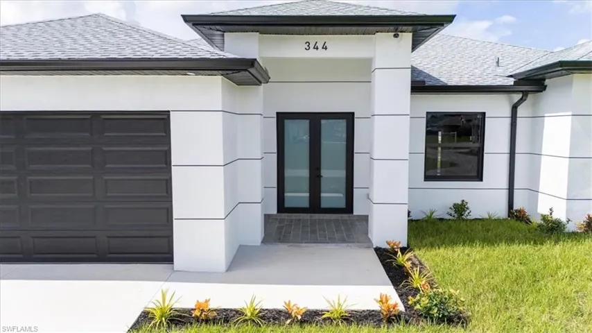 View of exterior entry with french doors, a garage, a shingled roof, stucco siding, and concrete driveway
