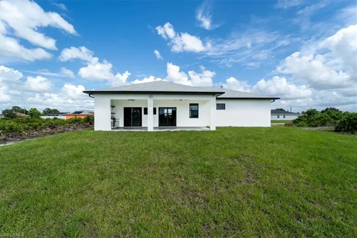 Rear view of property with a yard, a patio area, stucco siding, and a ceiling fan