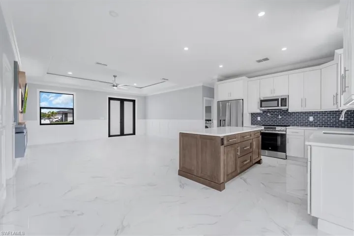 Dual tone kitchen with wainscoting, dual tone cabinets, crown molding, stainless steel appliances, and a ceiling fan
