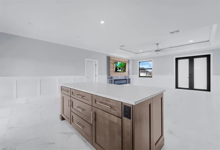 Kitchen featuring wainscoting, a center island, a decorative wall, recessed lighting, and ceiling fan