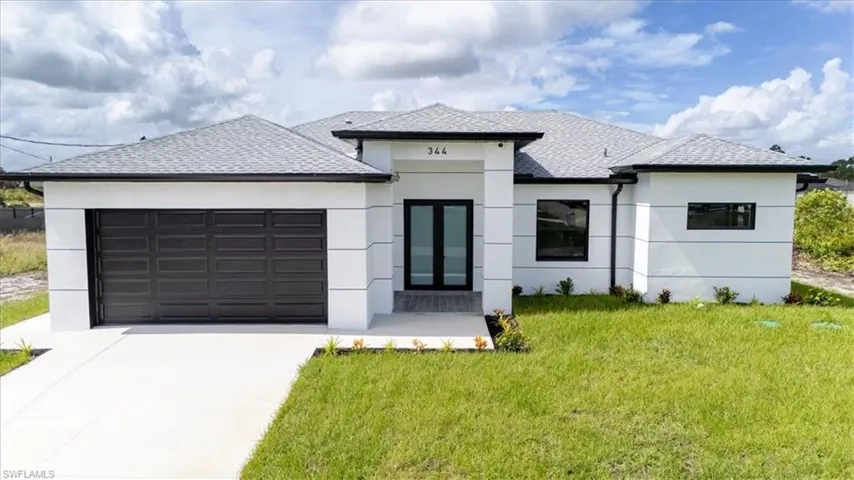 View of front facade with a garage, a front yard, roof with shingles, and stucco siding
