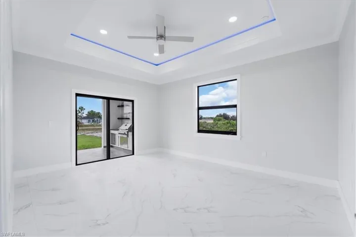 Spare room featuring light marble finish floors, a ceiling fan, recessed lighting, ornamental molding, and a tray ceiling