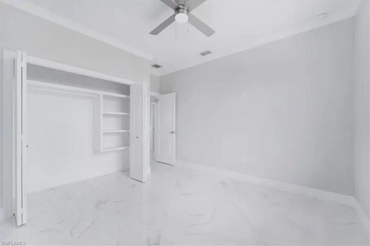 Unfurnished bedroom featuring a closet, ceiling fan, and light marble finish flooring