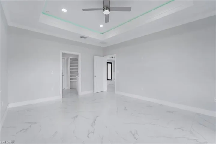 Empty room featuring crown molding, ceiling fan, a tray ceiling, and recessed lighting