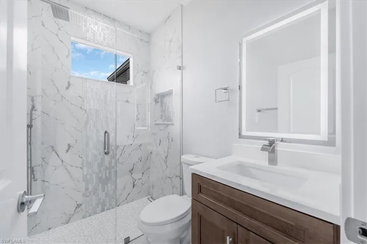 Bathroom with a marble finish shower and vanity