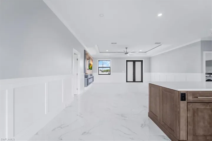 Corridor featuring a wainscoted wall, ornamental molding, recessed lighting, a decorative wall, and light marble finish flooring