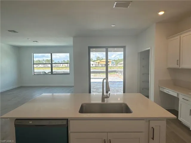 Kitchen with sink, dishwasher, a kitchen island with sink, and white cabinetry