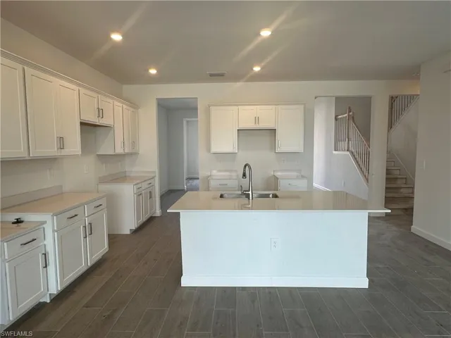Kitchen featuring sink, white cabinetry, an island with sink, and dark hardwood / wood-style floors