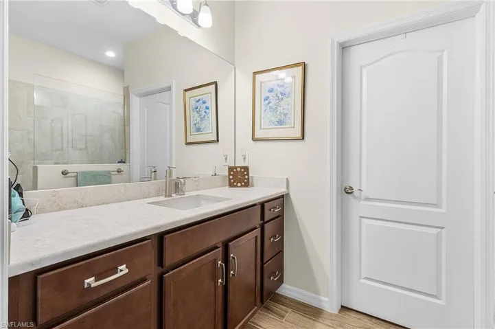 Full bathroom with vanity, a tile shower, light wood finished floors, and recessed lighting