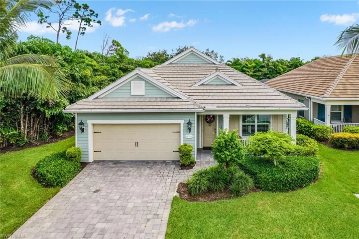 View of front of property with decorative driveway, a front yard, an attached garage, and a tiled roof