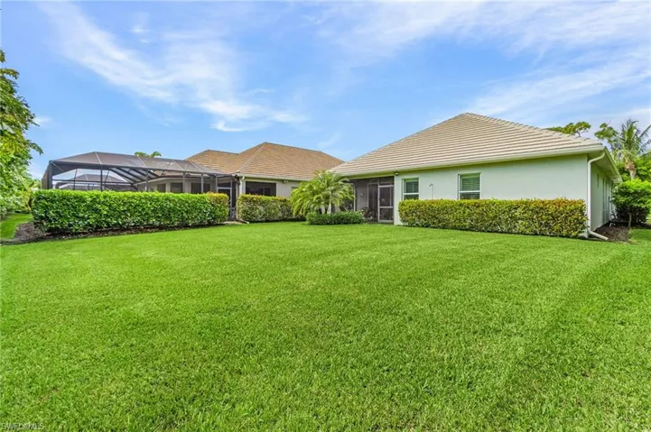 Rear view of property with a sunroom, a lawn, stucco siding, and a lanai