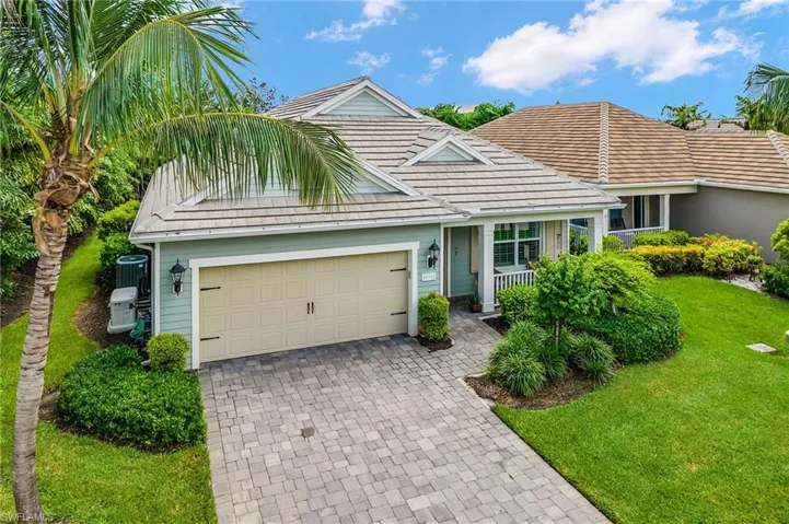 View of front of home with decorative driveway, a front yard, and an attached garage