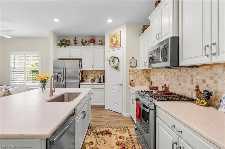 Kitchen featuring stainless steel appliances, white cabinets, light wood-type flooring, recessed lighting, and a kitchen island with sink
