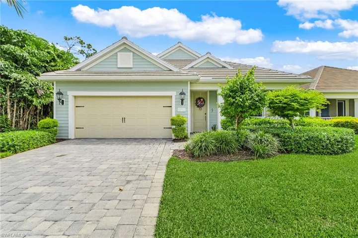 Ranch-style home with decorative driveway, a front lawn, and an attached garage